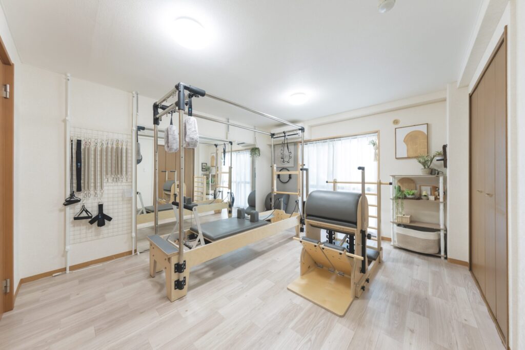 清潔感のある明るいピラティススタジオの全景、各種マシンやミラーが整然と配置された空間